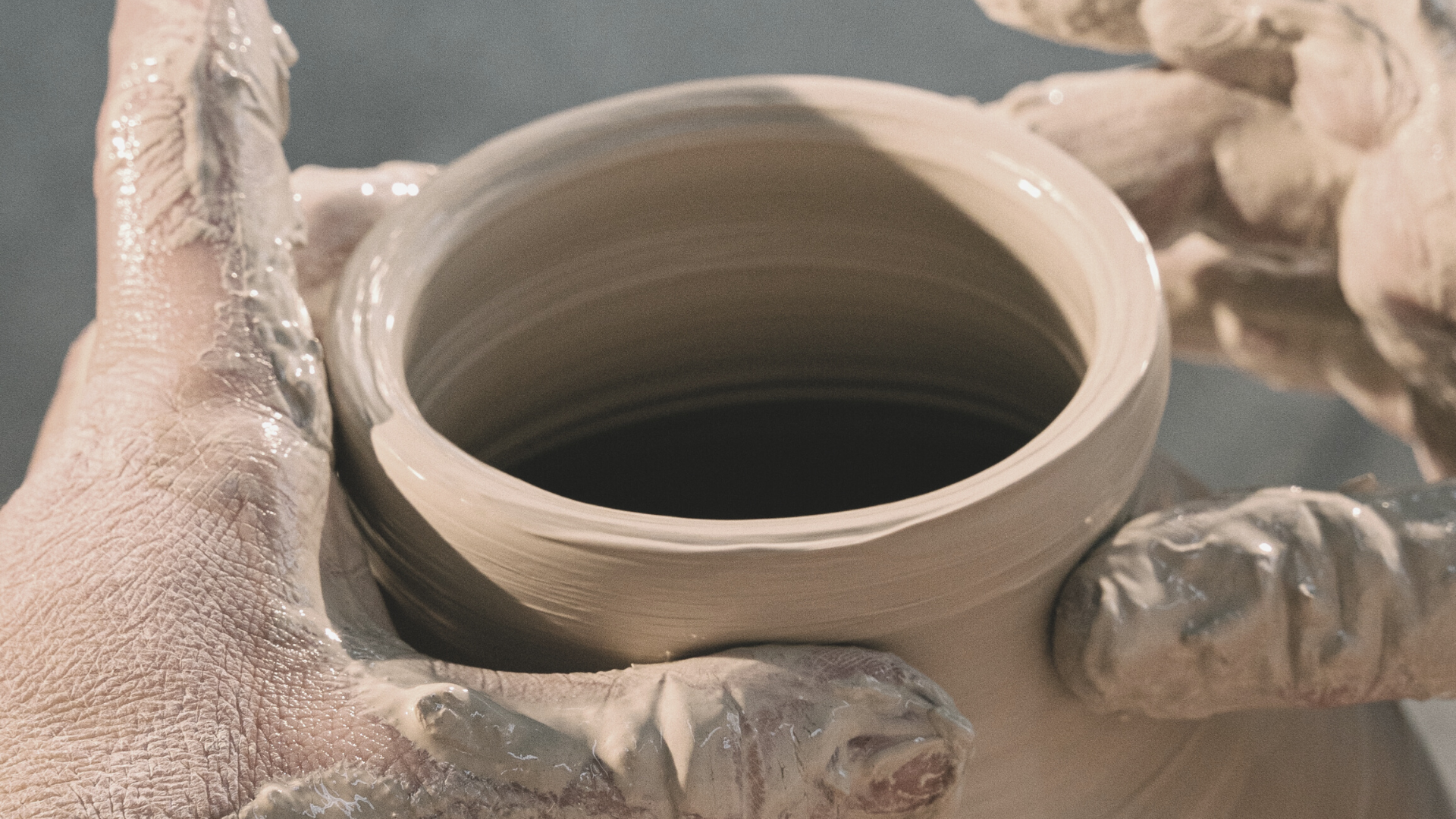 close up of clay vase and two hands